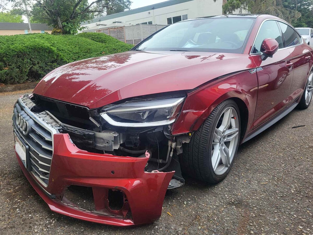 Front of a red Audi A5 Sportback as it arrived, the bumper pulled away from the fender and the headlamp surround broken open