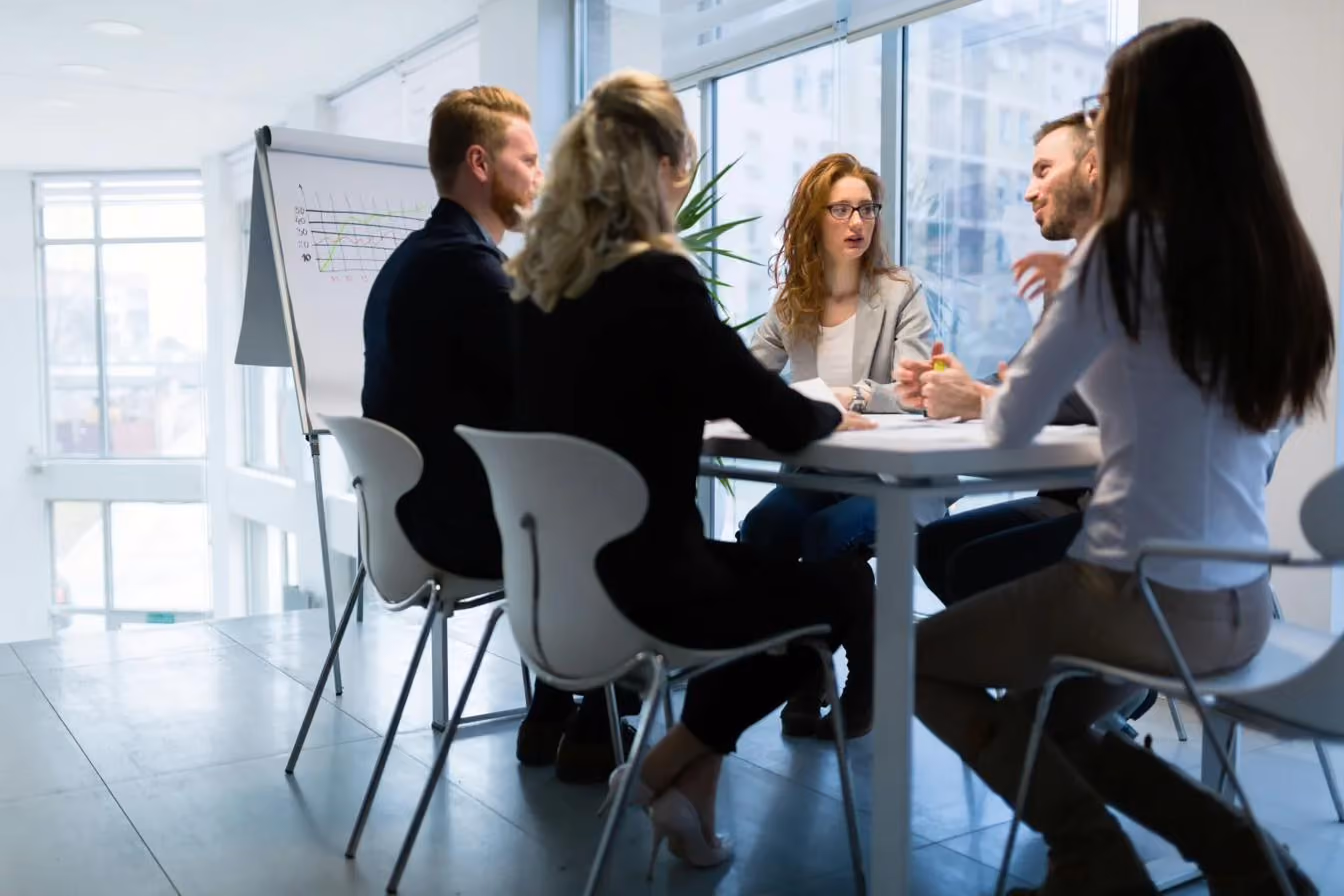 Five colleagues in a meeting around a table in a bright office