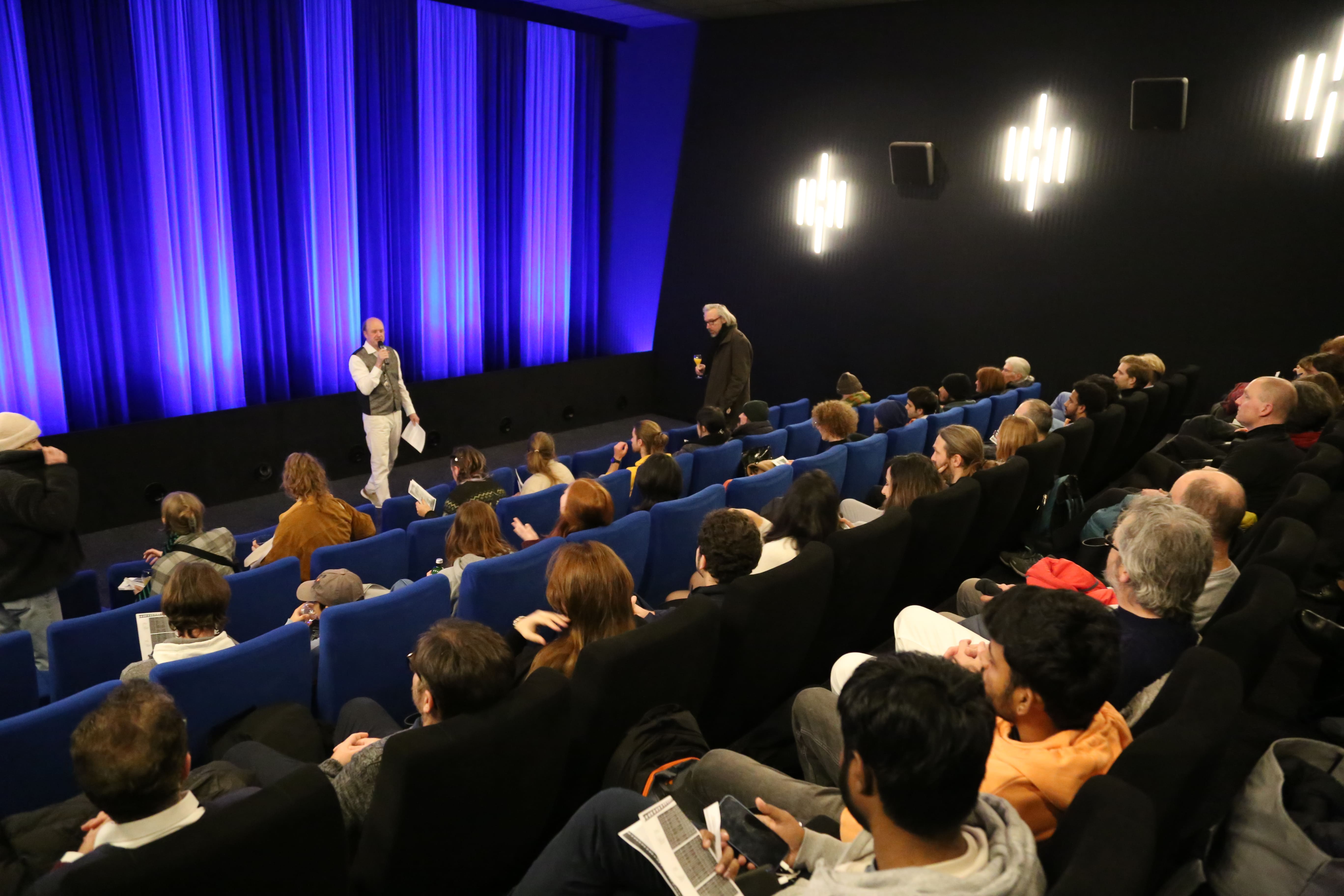 Begrüßung des Publikums vor dem blauen Kinovorhang
