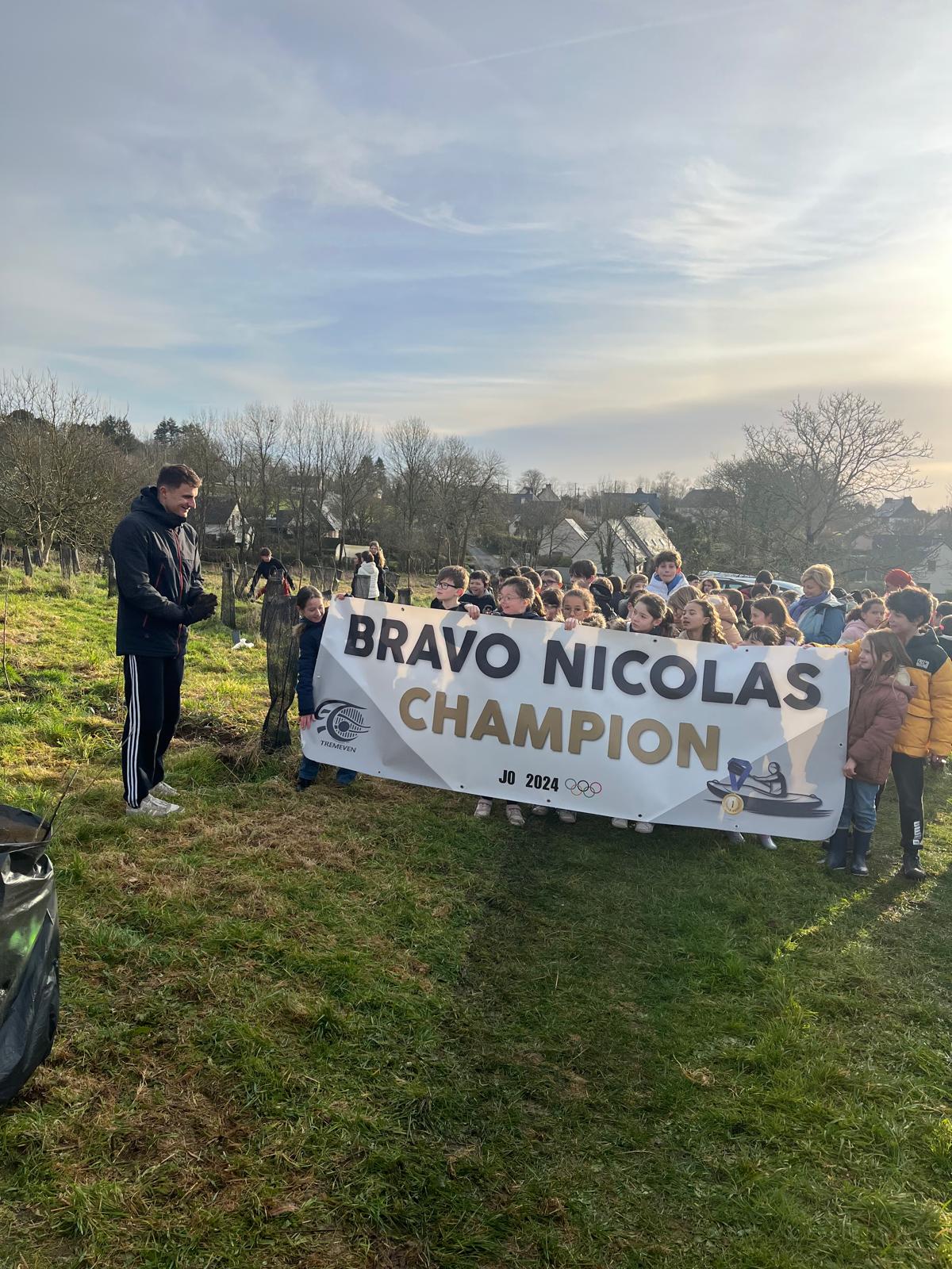 Élèves avec une banderole « Bravo Nicolas champion » lors de la plantation 2025
