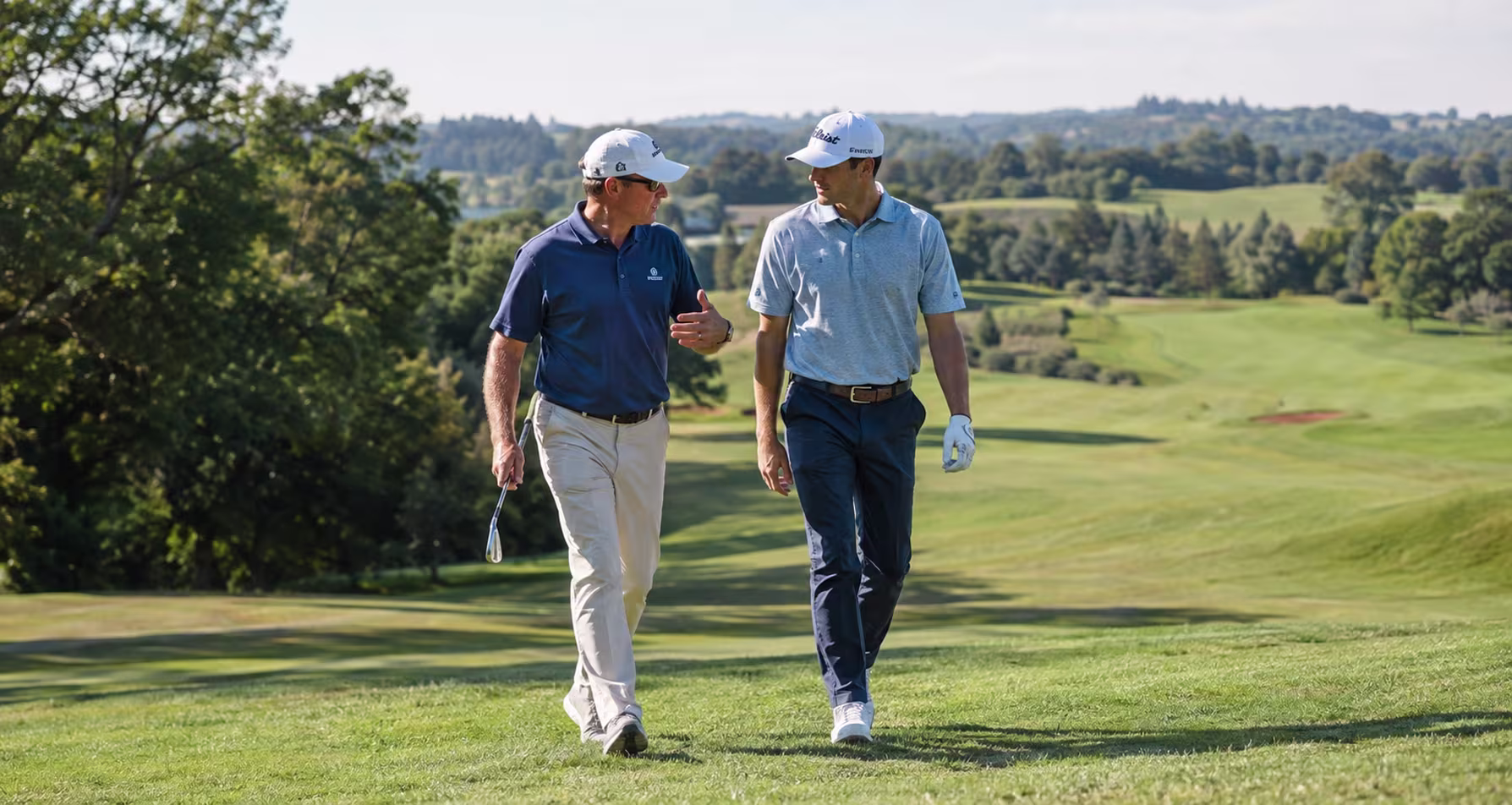 Golf coach and player walking together across the fairway discussing course strategy