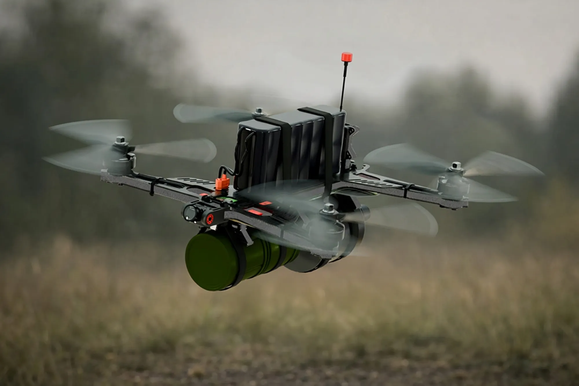 Quadcopter drone equipped with a mounted green container flying over a blurred outdoor field.