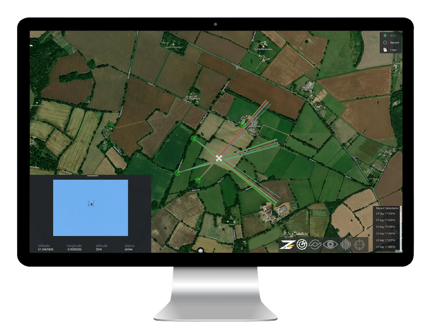 コンピューター画面に表示された衛星画像の地図で、中央にドローンアイコンと複数の色付き線が放射状に伸びている。左下にドローンのリアルタイム映像と位置情報、ステータスが表示されている。地図は田畑や林、道路で区切られた農村地域を示している。
