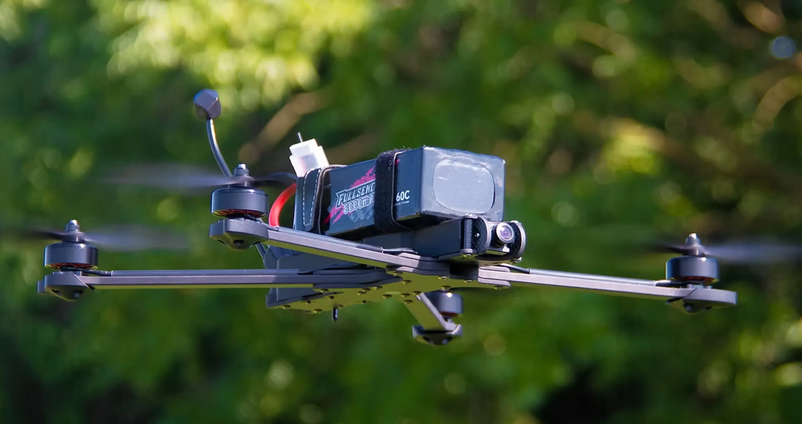 カメラを搭載し、4つのプロペラが回転して飛行中のレーシングドローン。