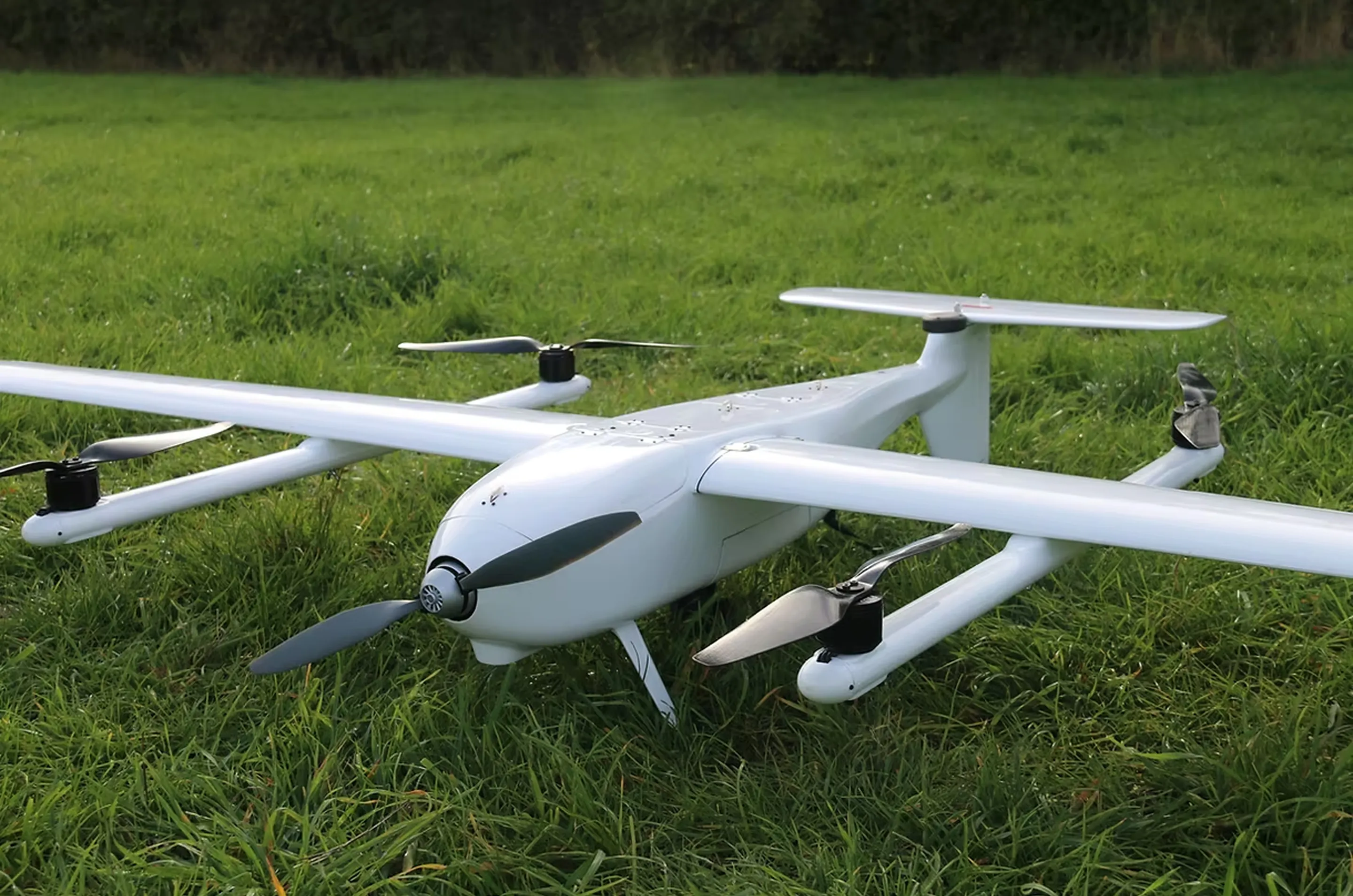 緑の草地に停まっている白色の複数プロペラを持つ無人機ドローン。