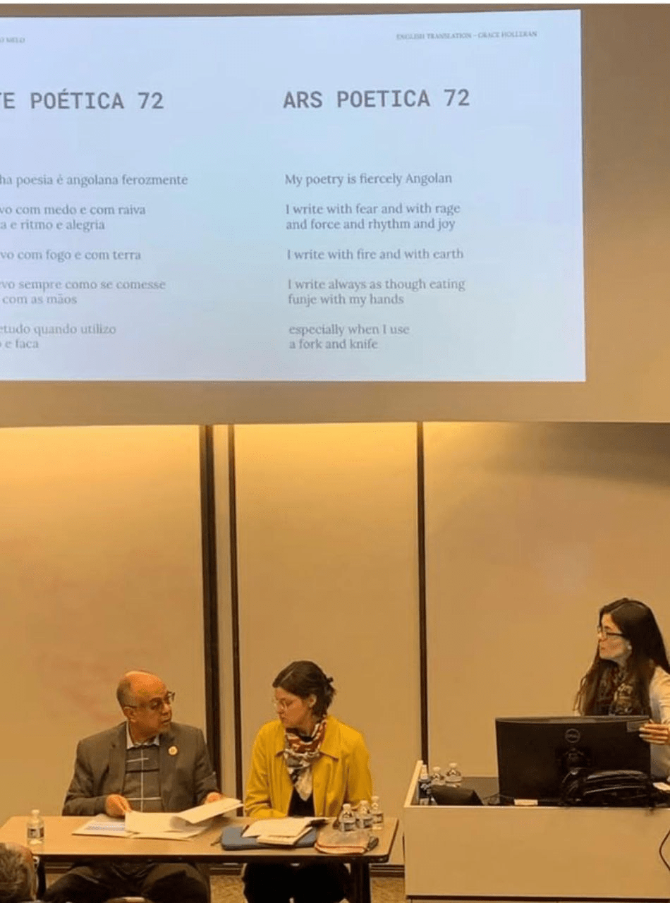 Three panelists at a table beneath a projected bilingual poem titled Ars Poetica 72, with a speaker standing at a lectern.