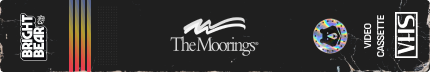 Black VHS tape label with Bright Bear logo on the left, a vertical gradient stripe of red, orange, and yellow in the center, The Moorings logo in white in the middle, VHS video cassette icon on the right, and a rainbow-colored circular emblem near the VHS icon.