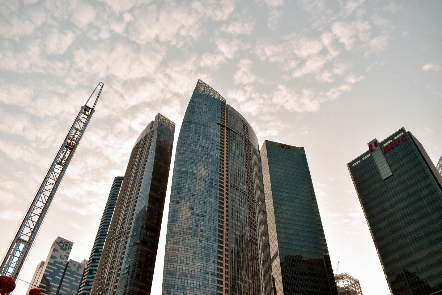 Low view of tall buildings under a cloudy skyDescription automatically generated