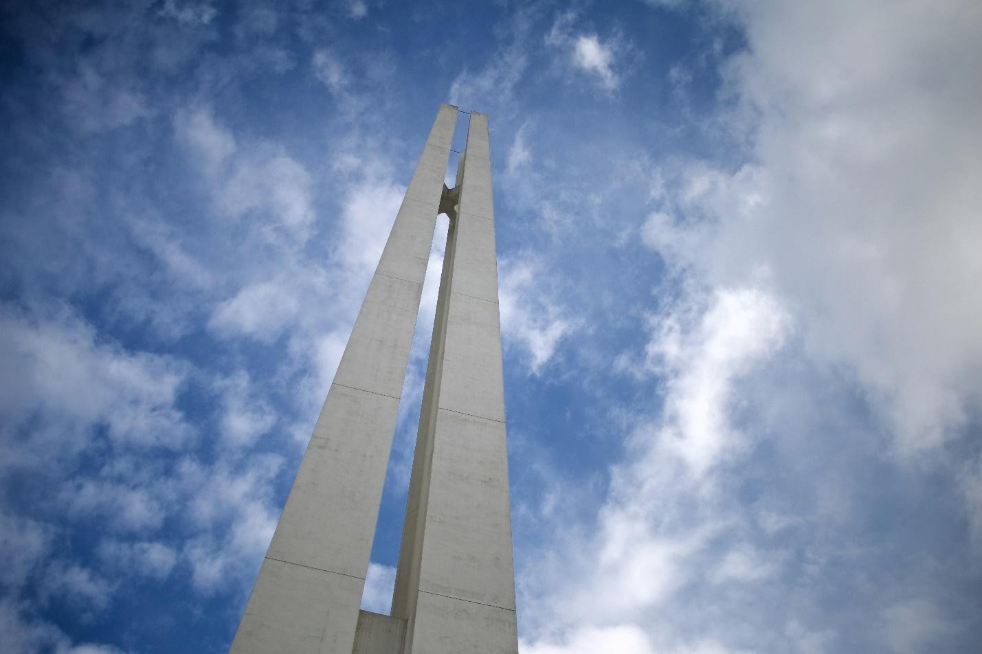 A tall white tower with blue sky and cloudsDescription automatically generated