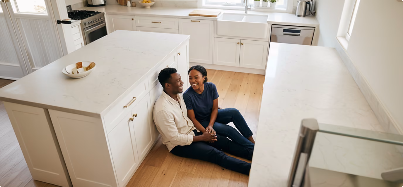 Couple sitting on their kitchen floor laughing together