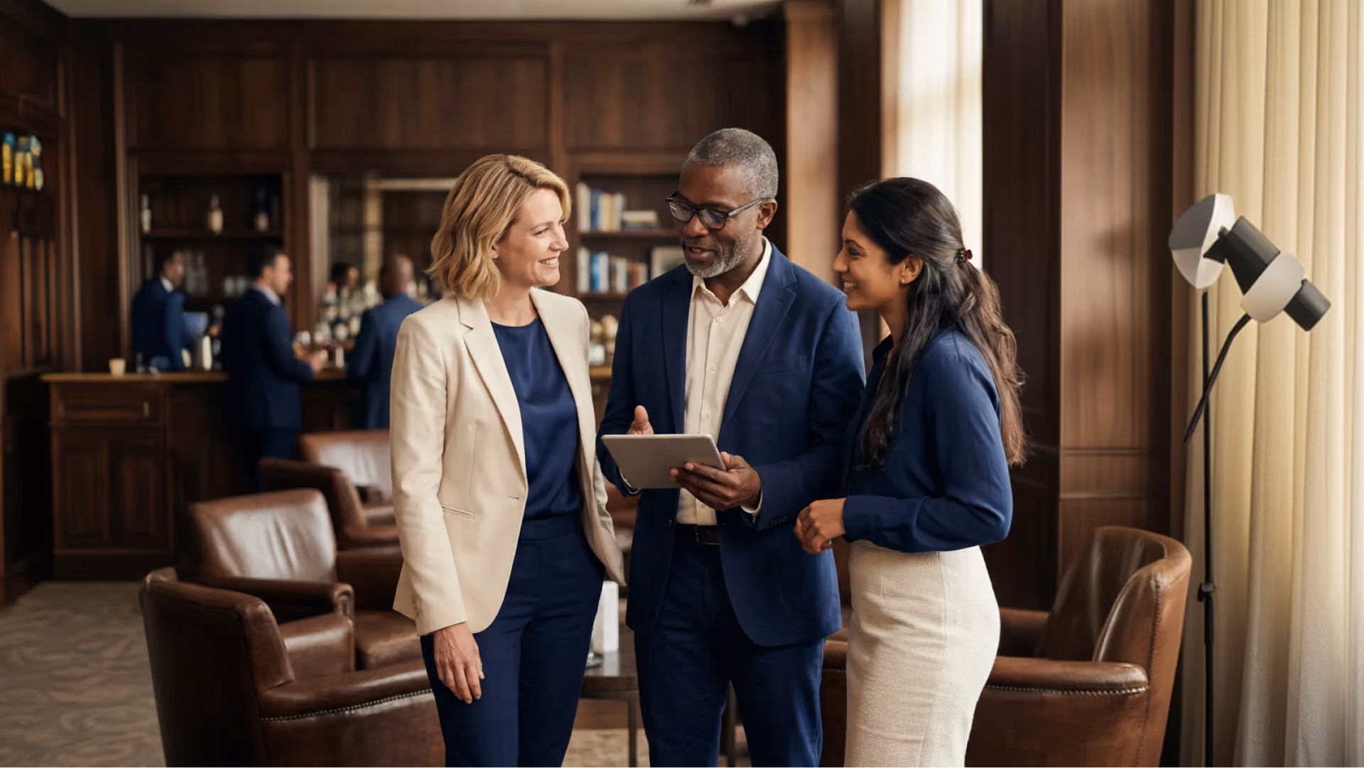 Three professionals chatting and reviewing a tablet together in a wood-panelled lounge
