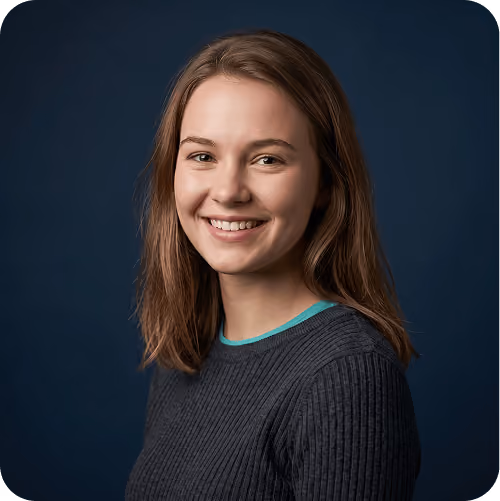 Studio headshot of a smiling woman with long brown hair against a navy backdrop