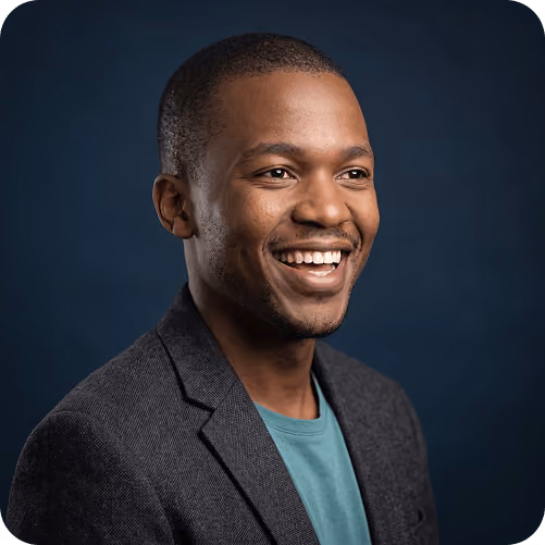 Studio headshot of a smiling man in a blazer against a navy backdrop