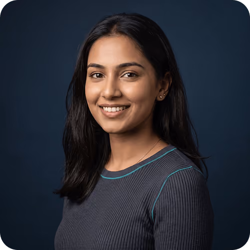 Studio headshot of a smiling woman in a grey top against a navy backdrop