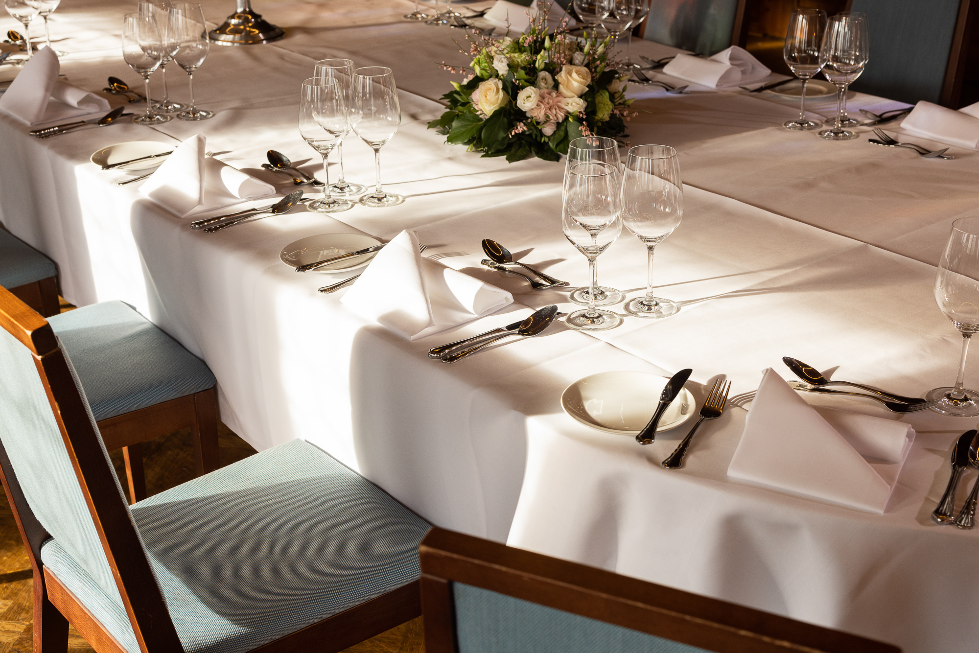 Weiss gedeckte Tafel mit Rosengesteck und Gläsern im Zunfthaus zur Waag