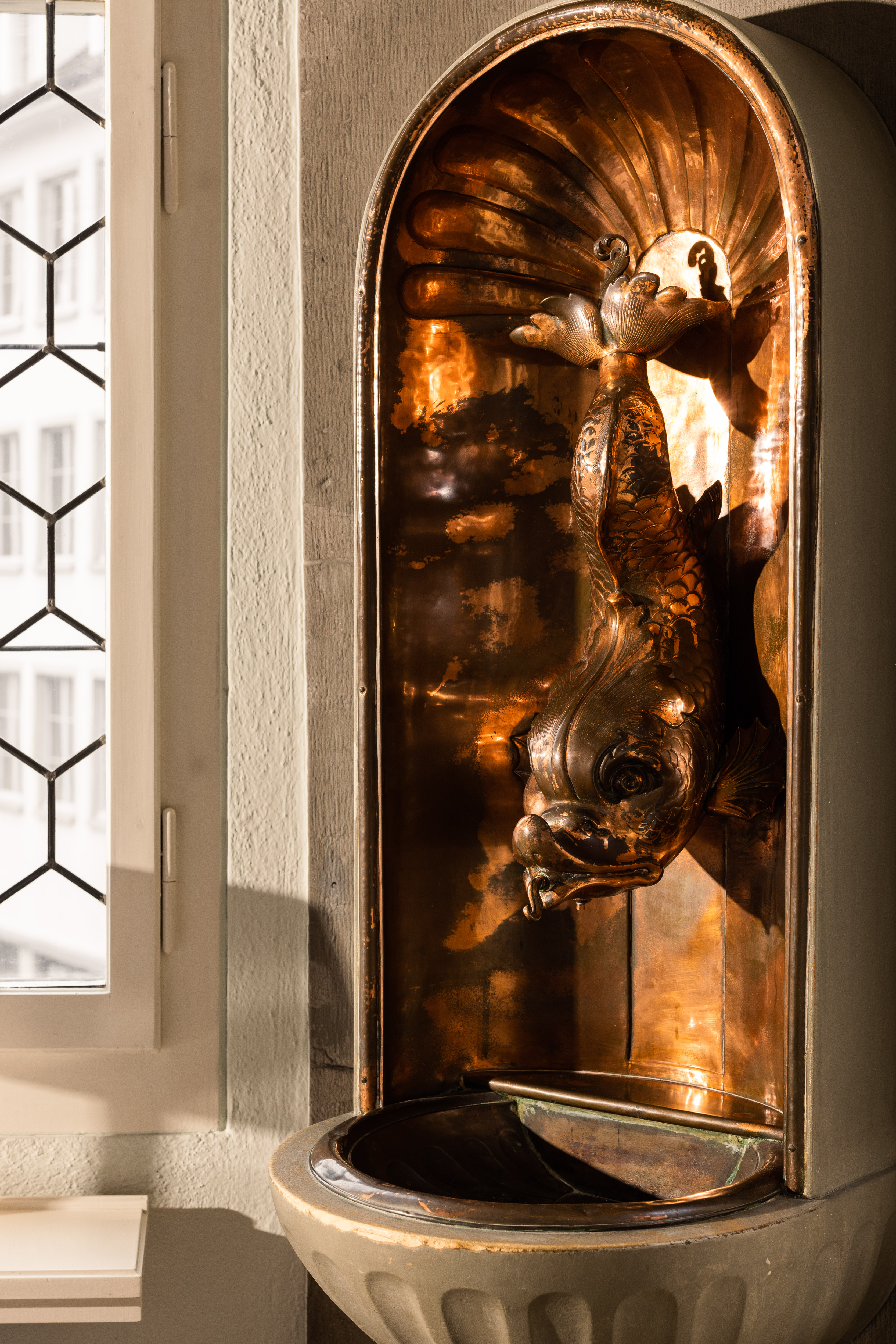 Kupferner Wandbrunnen mit Fischfigur in einer Nische im Zunfthaus zur Waag