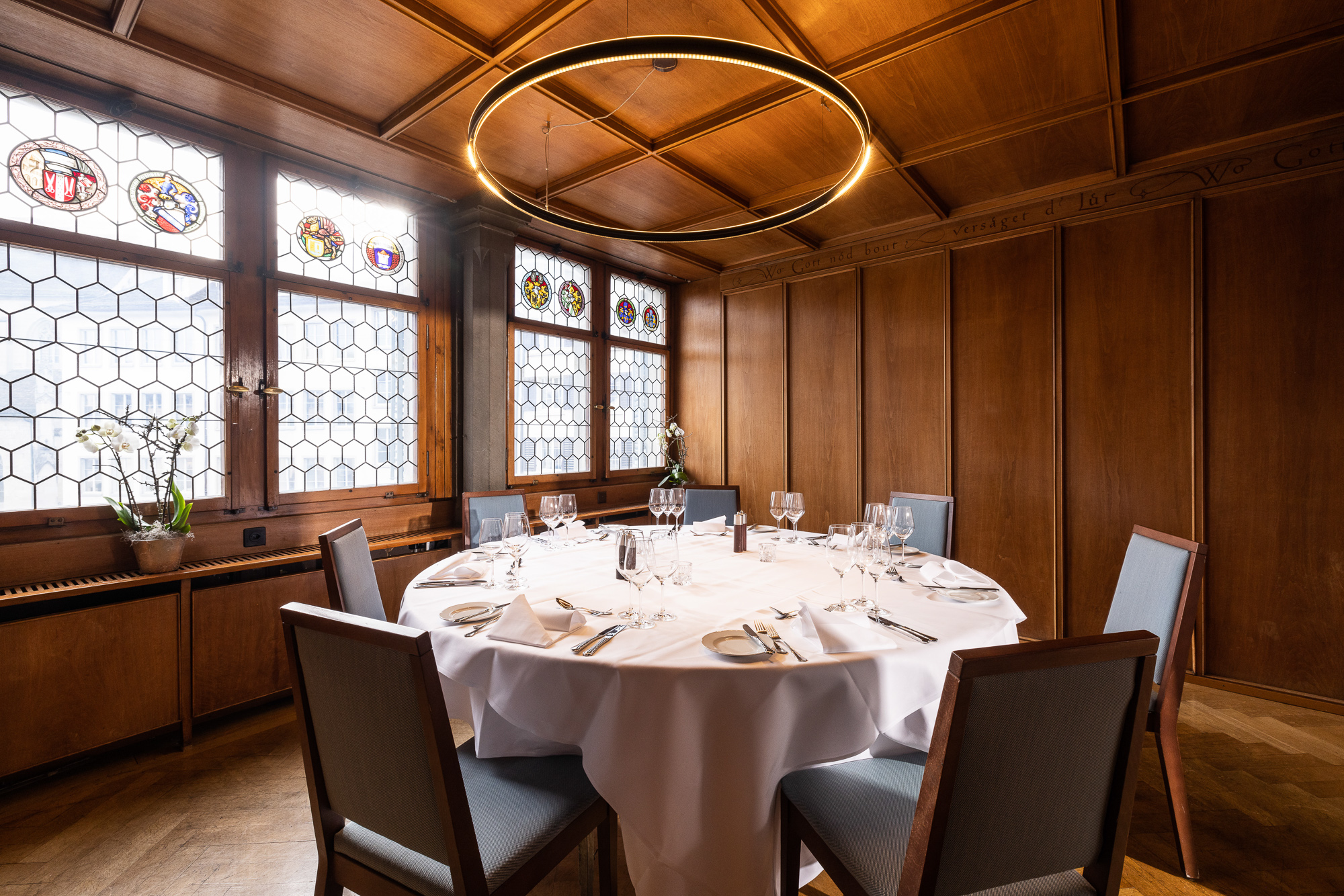 Laid round table beneath the ring chandelier in the wood-panelled Waagstübli