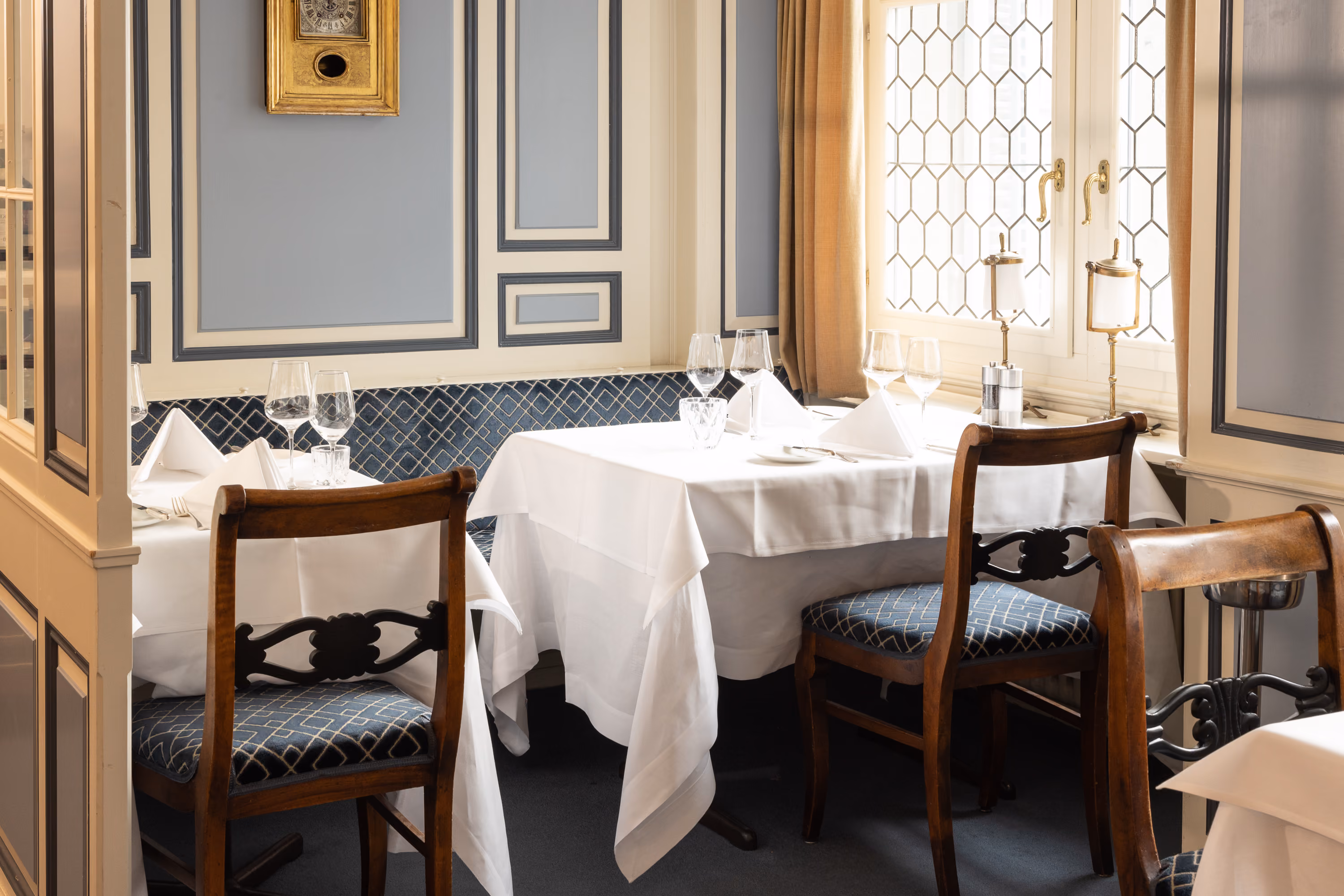 Gedeckte Tische mit Holzstühlen vor blau-weissen Wänden im Restaurant des Zunfthauses zur Waag