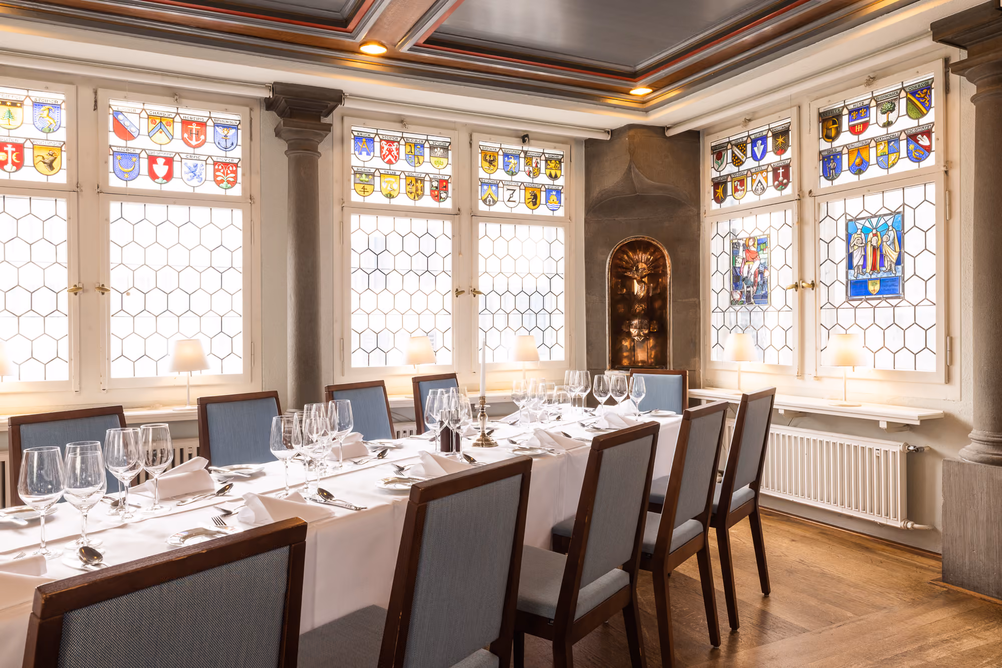Helle Zunftstube mit farbigen Wappenscheiben und langer gedeckter Tafel im Zunfthaus zur Waag