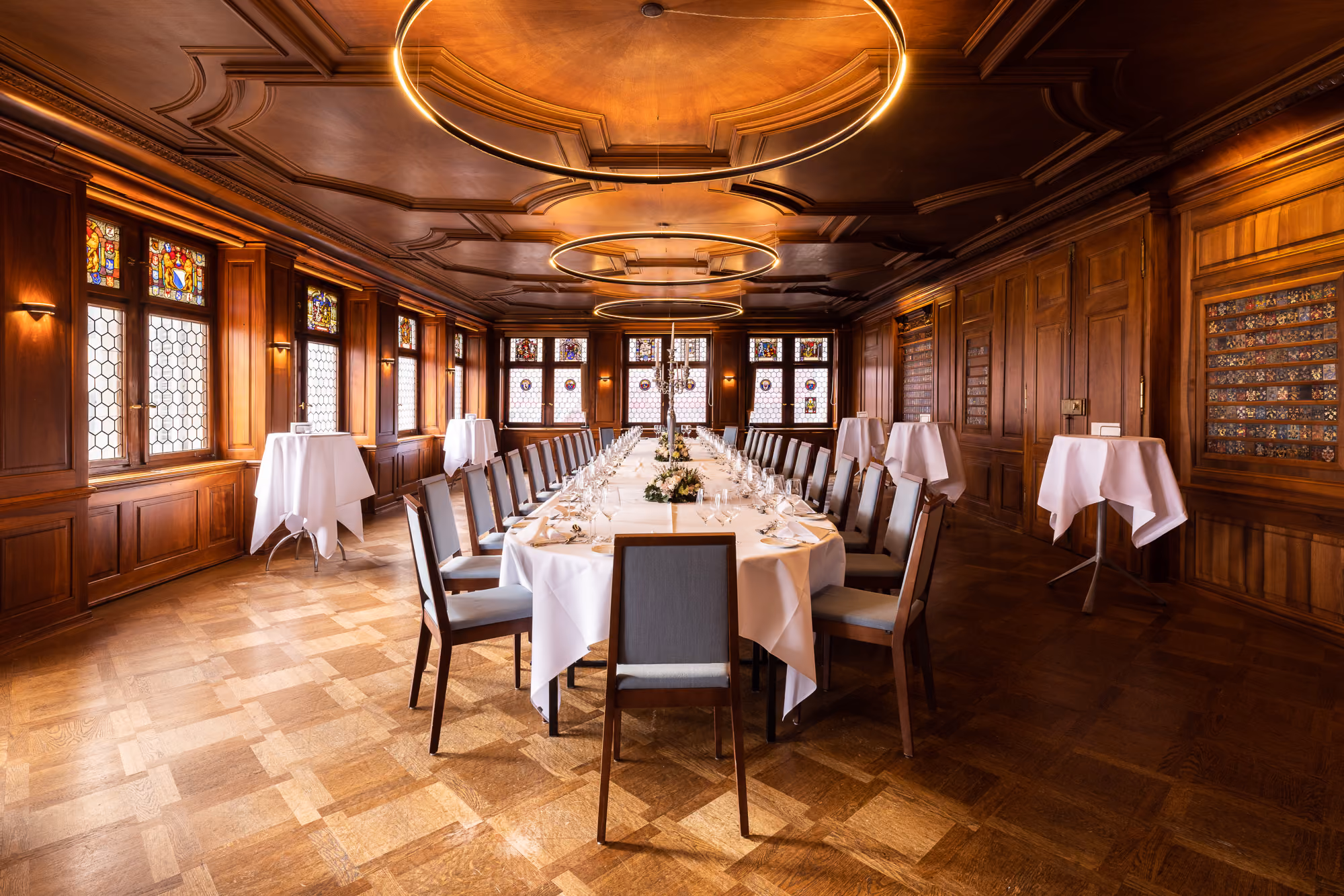 Zunftsaal mit langer Bankett-Tafel, Stehtischen, Holztäferung und Ringleuchtern im Zunfthaus zur Waag