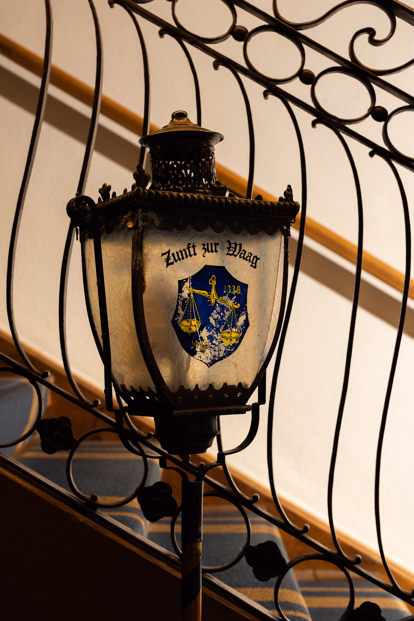 Laterne mit Aufschrift «Zunft zur Waag» und Waage-Wappen am schmiedeeisernen Treppengeländer