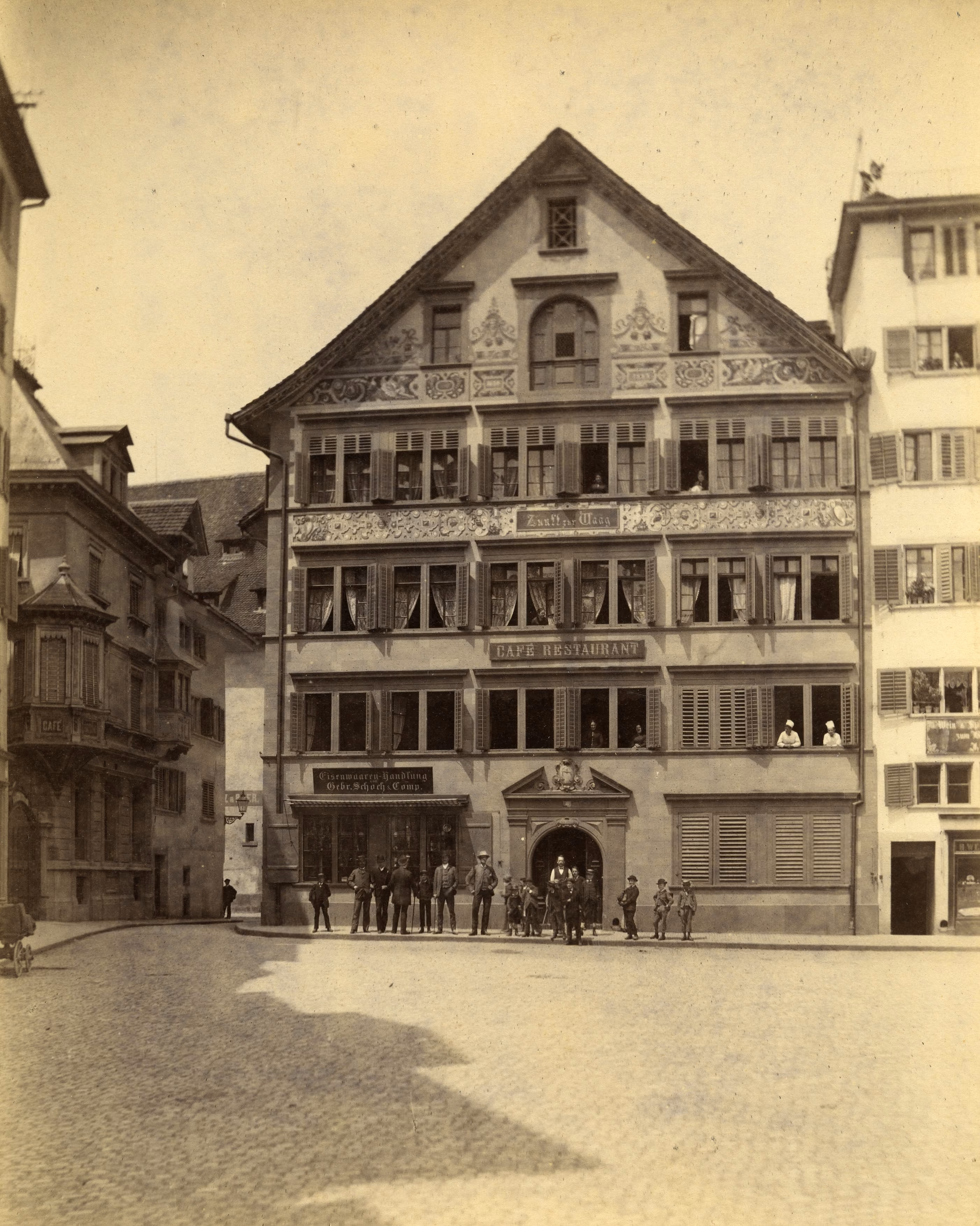 Historische Aufnahme der verzierten Fassade des Zunfthauses zur Waag mit Schriftzug «Café Restaurant» und Menschen vor dem Eingang