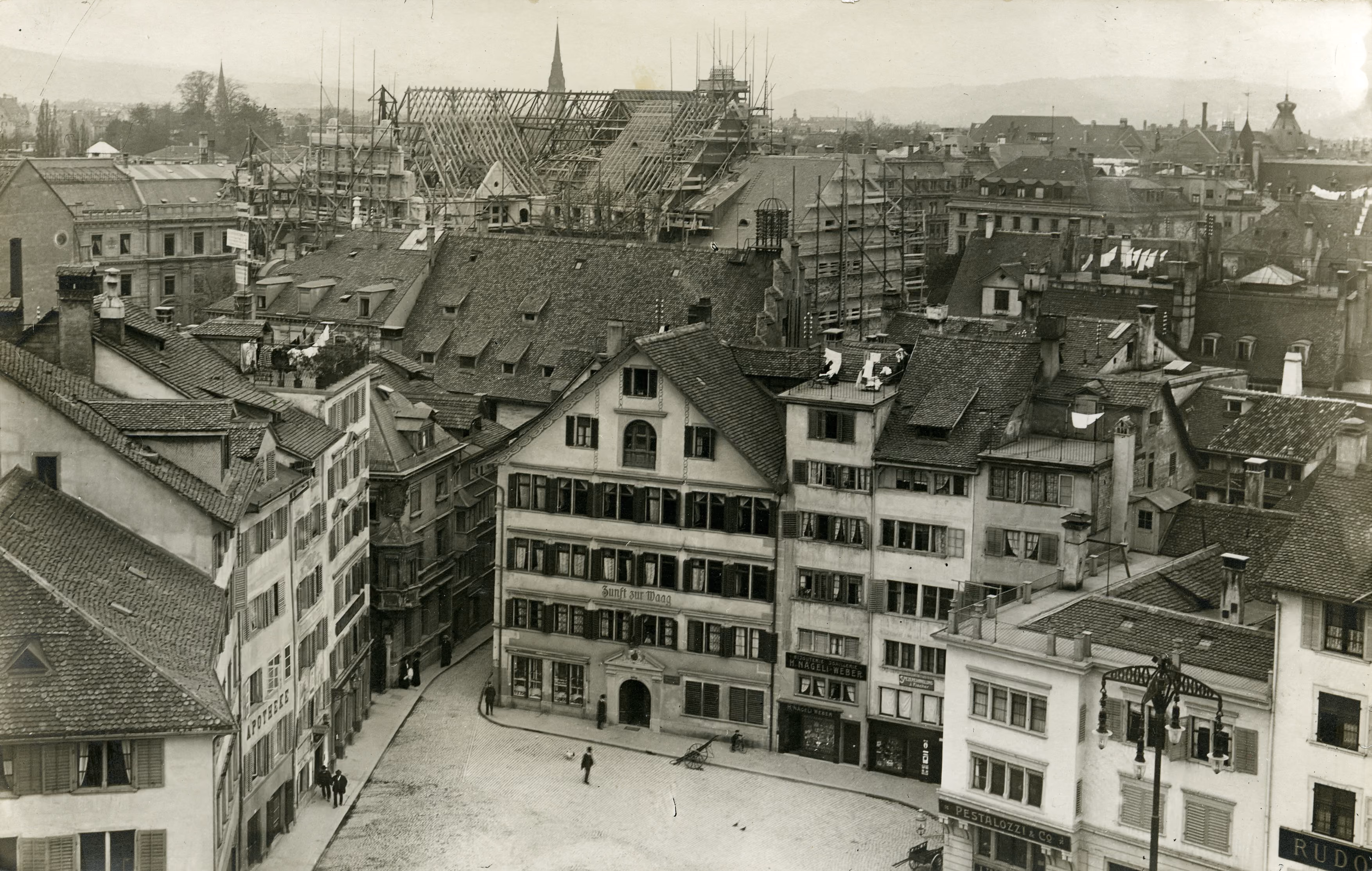 Historische Aufnahme von oben auf den Münsterhof und das Zunfthaus zur Waag, im Hintergrund eingerüstete Dächer