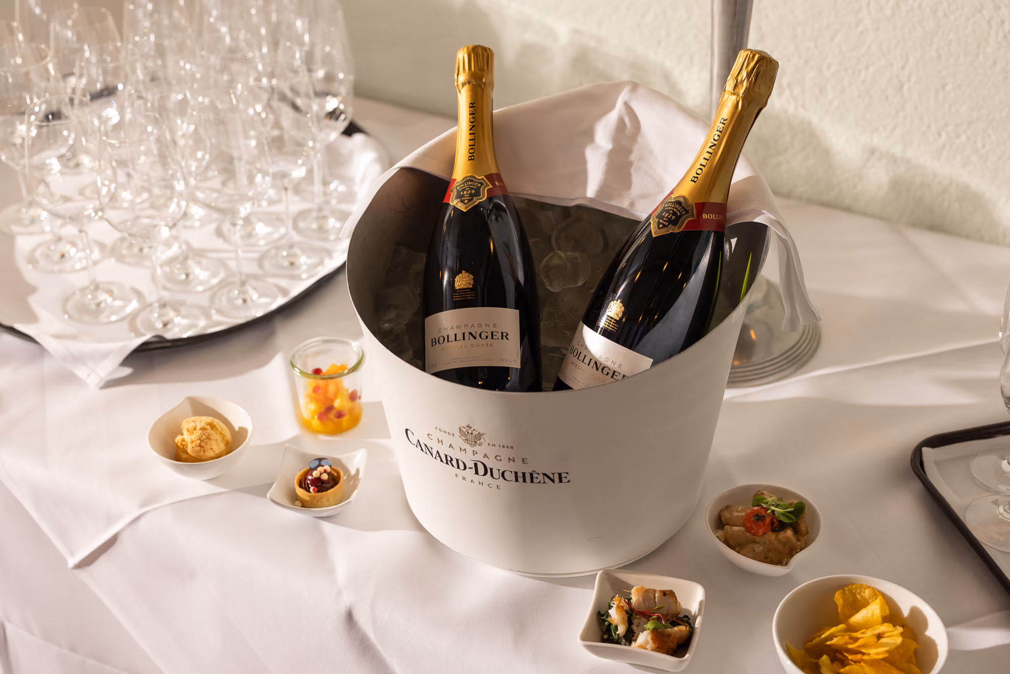 Apéro mit Champagnerflaschen im Kühler, Gläsern und kleinen Apéro-Häppchen
