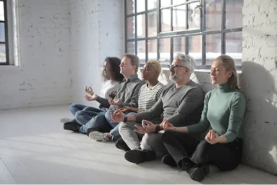 Équipe en méditation assise contre un mur, pendant une séance en entreprise