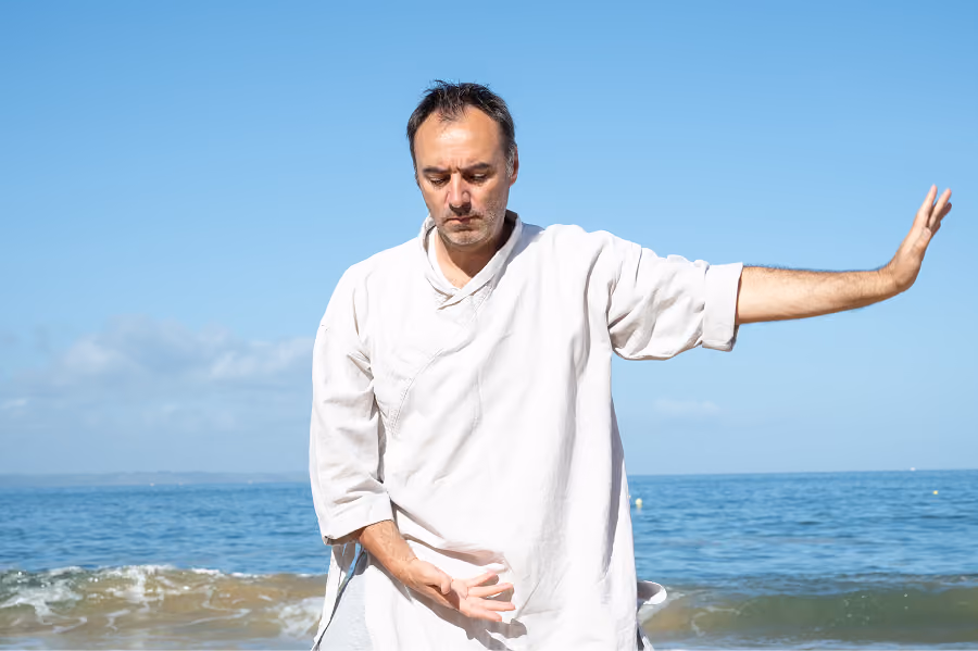 Gilles Le Picard en posture de Qi Gong face à la mer