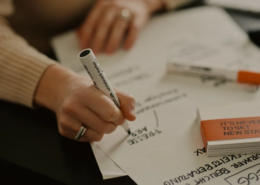 Hand sketching a diagram on paper with a whiteboard marker