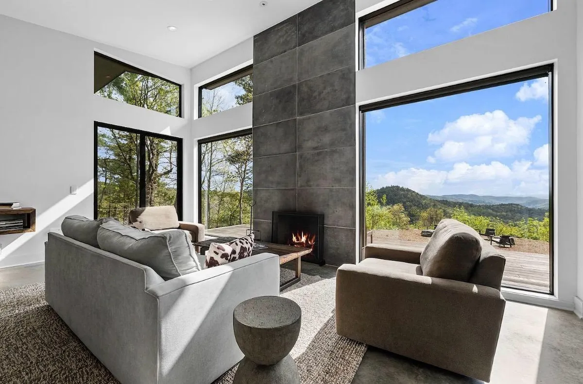 Living room at Lost Ridge with the stone hearth and mountain views through walls of glass