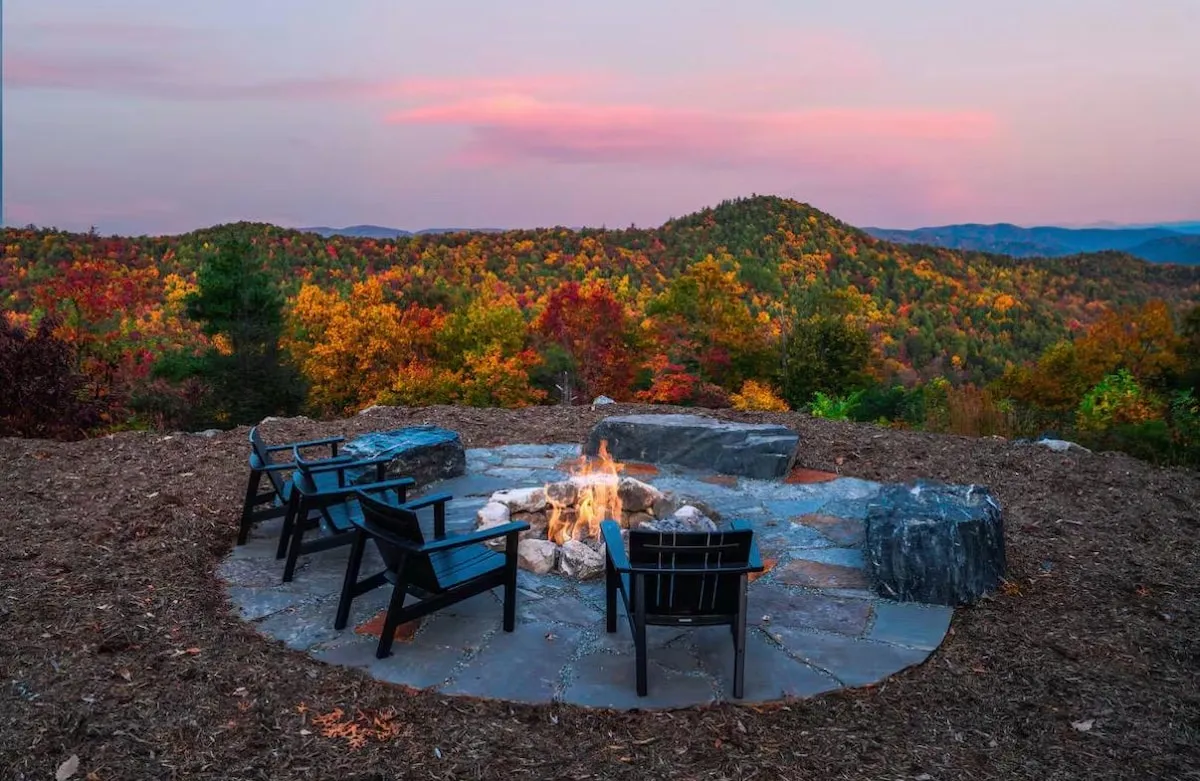 Two chairs beside the stone fire pit at Lost Ridge as the sun sets over the mountains