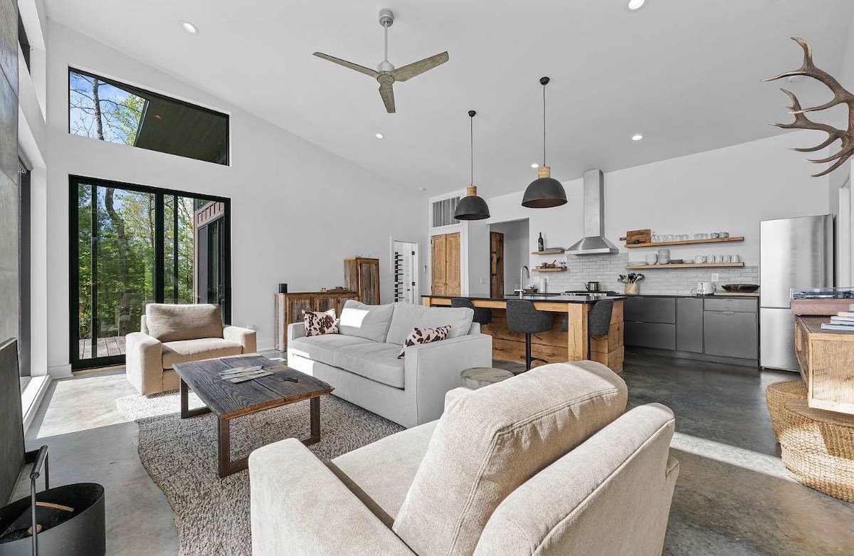 Open-plan living room and kitchen under a vaulted ceiling with polished concrete floors
