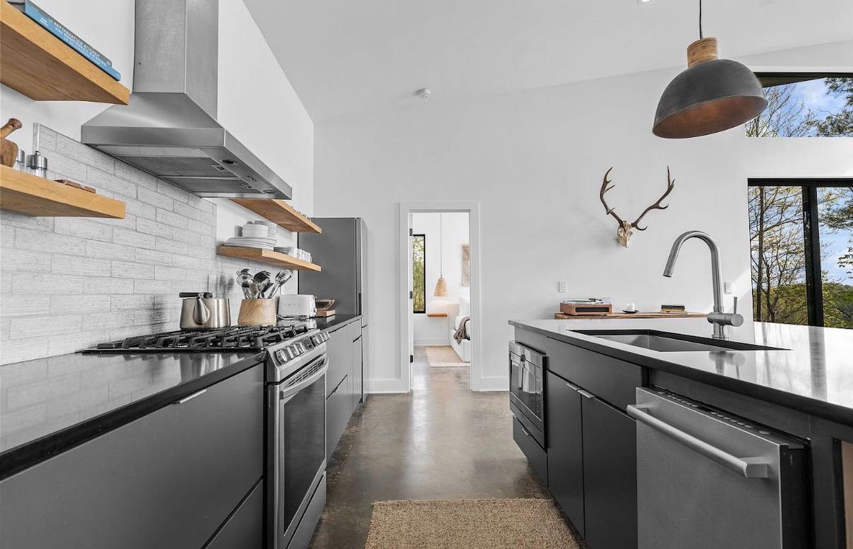 Galley kitchen with a gas range, open oak shelving, and a view through to the king suite