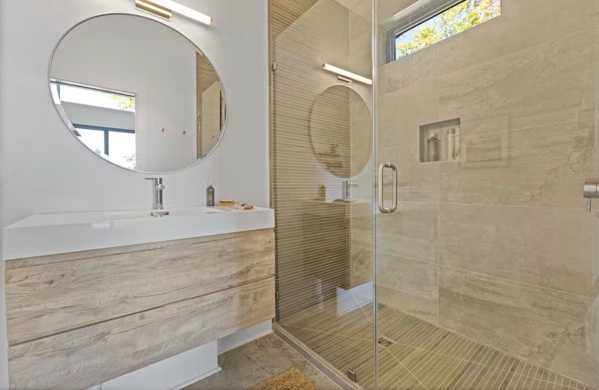 Walk-in tiled shower and oak vanity in the private bath
