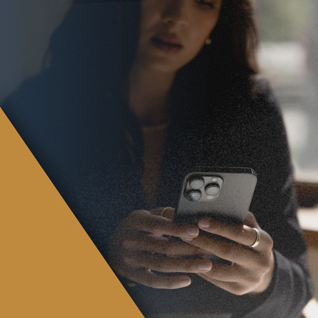 A woman in a dark coat looking at a phone, framed by a gold brand triangle.