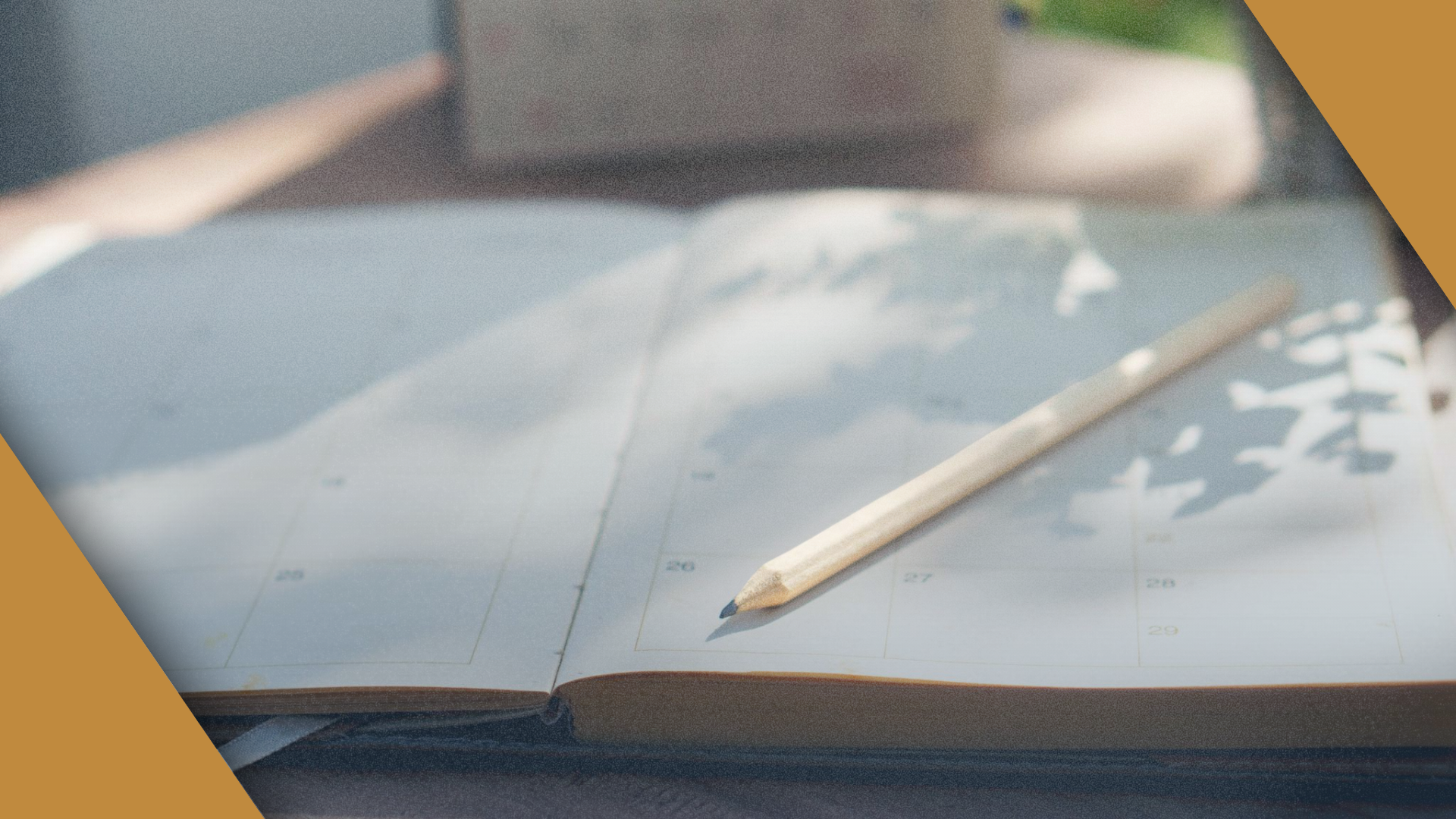 An open planner with a pencil on the page, framed by gold brand corners.