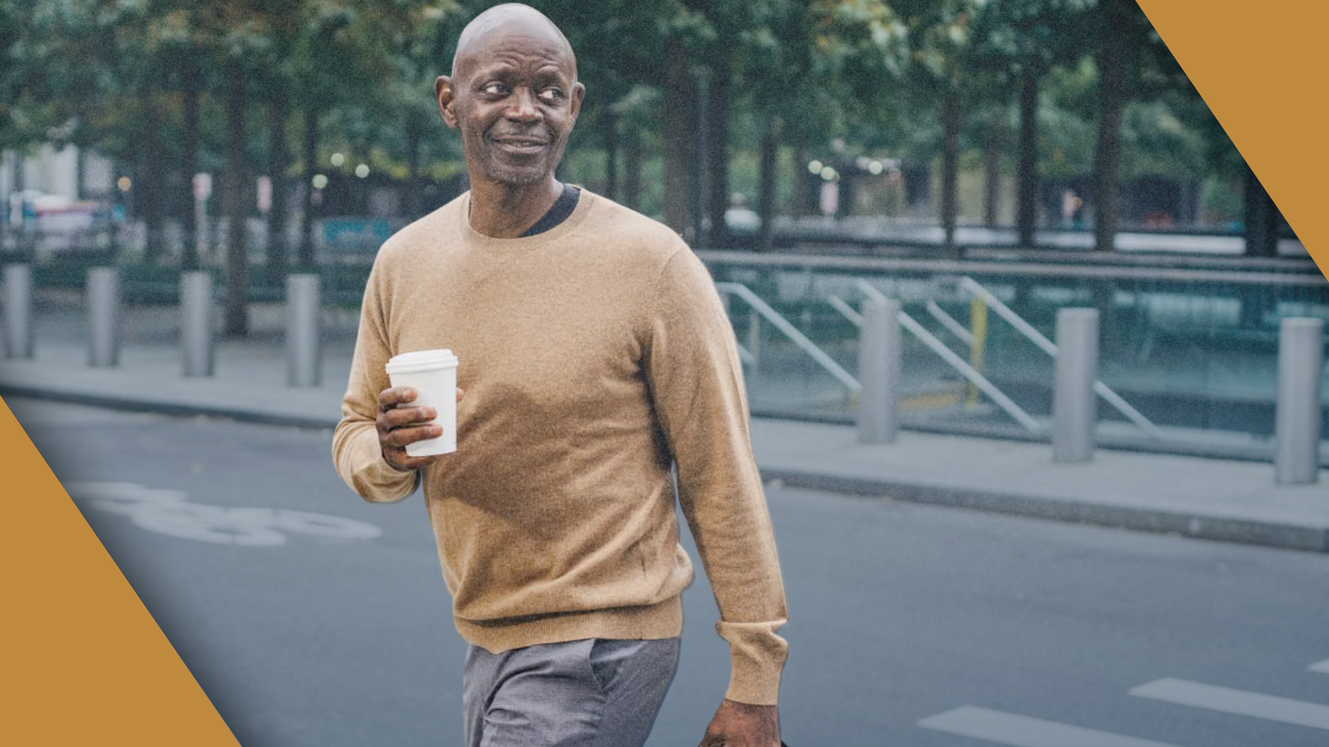 A man walking through a city plaza with a coffee cup.