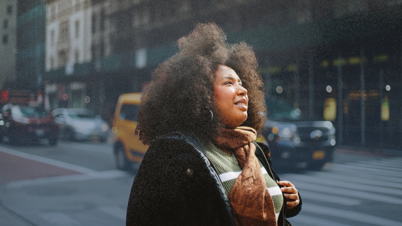 A woman in a winter coat looking ahead on a city street.