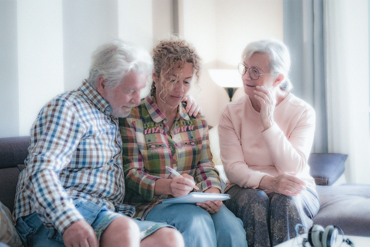 Adult daughter and her parents writing in a planning notebook