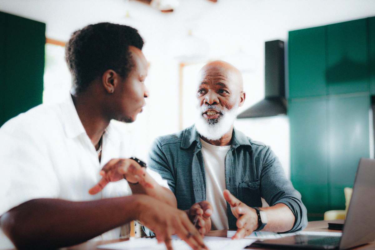 Adult son and his father reviewing documents at a kitchen table