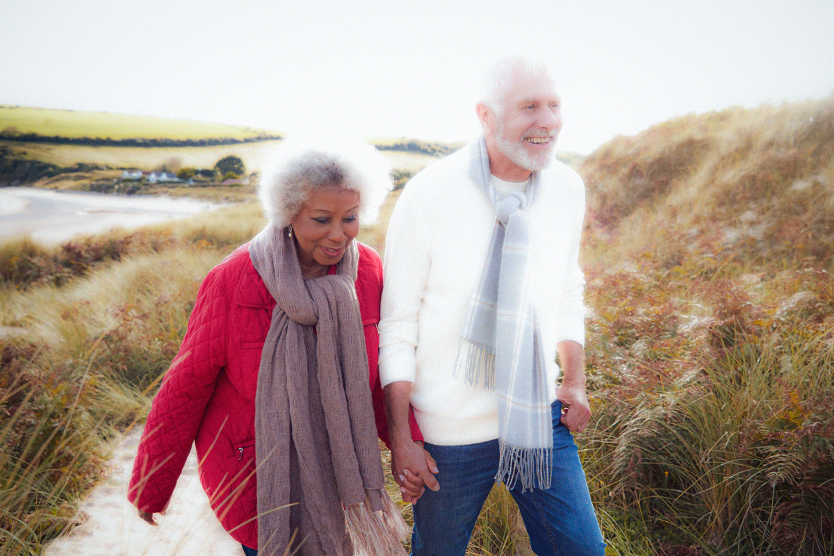 Older couple walking hand in hand on a coastal path