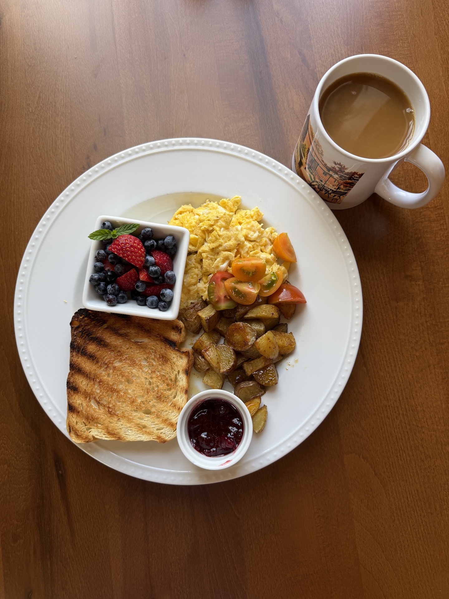 A photo of a plate with toast, eggs, and jam, alongside a mug of coffee
