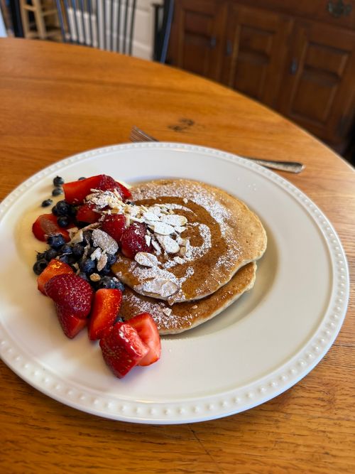 A photo of a plate with pancakes and strawberries