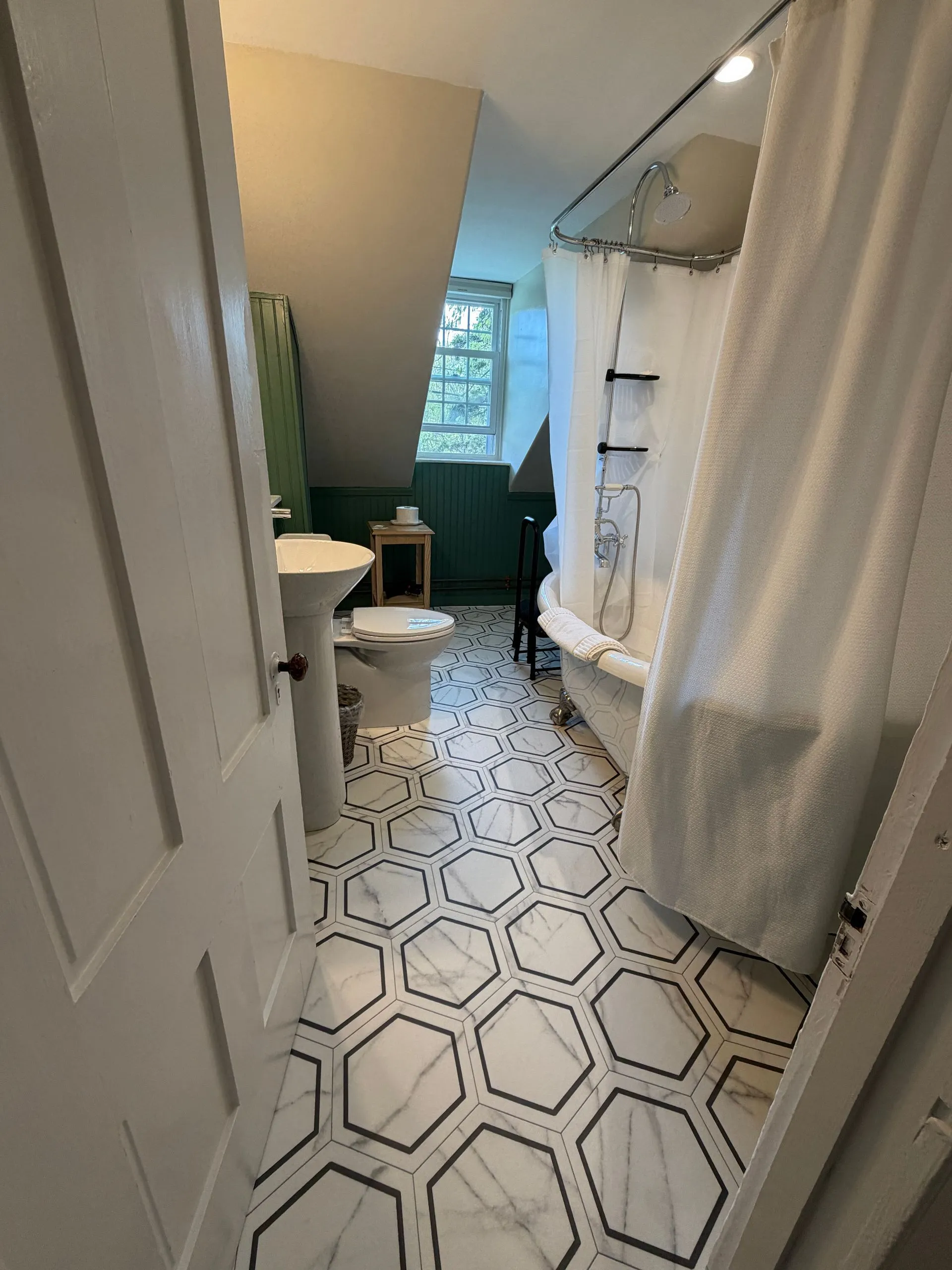 Private bathroom with clawfoot tub and shower in the Abbe suite at Coach Stop Inn