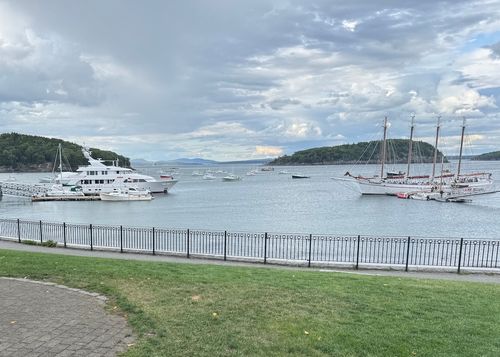 A view of a harbor with a large sailboat and tour boat seen in the distance