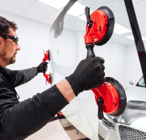 Technician installing a windshield with suction cups