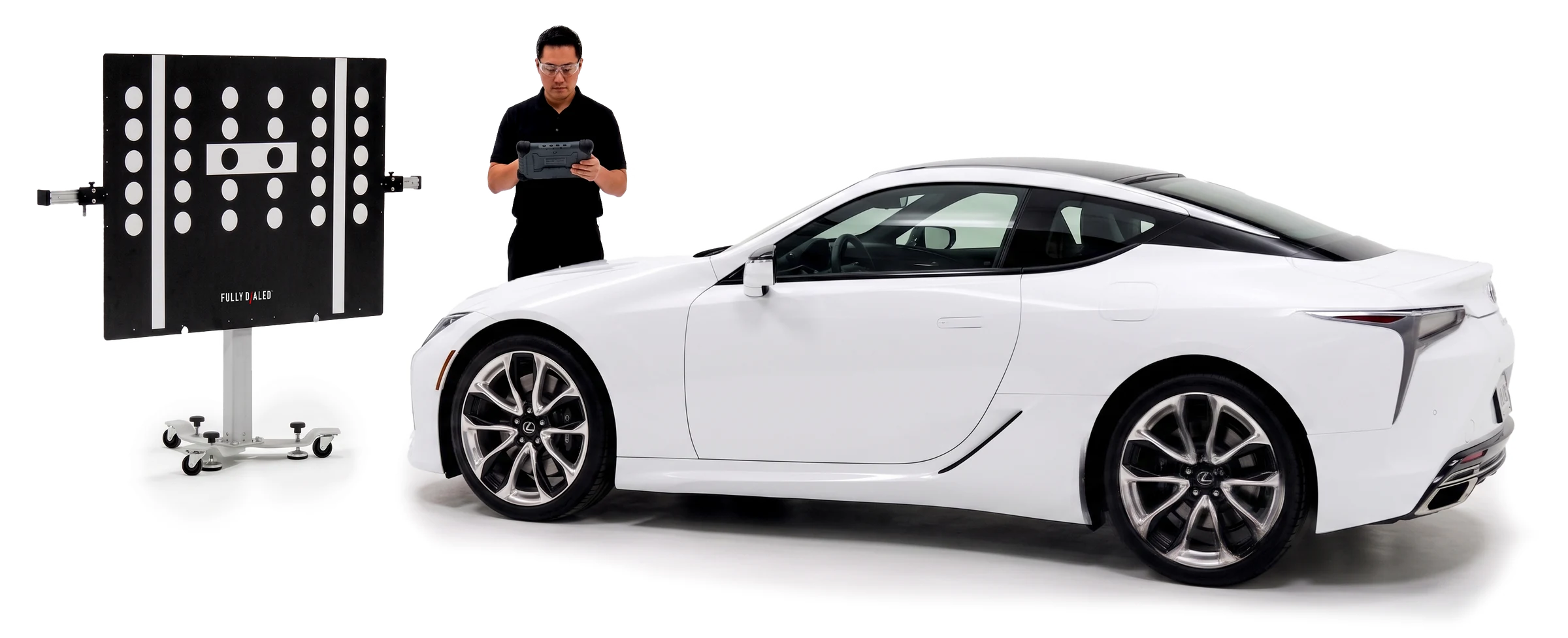 Technician with a tablet behind an ADAS calibration target next to a white Lexus
