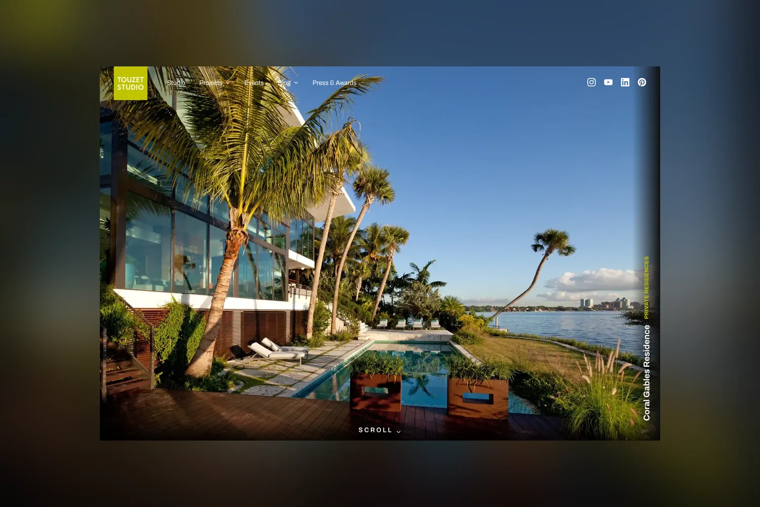 The Touzet Studio homepage with a full-bleed waterfront residence photograph and a scroll prompt